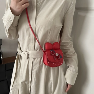 Petit sac carré rouge à bandoulière avec nœud et motif poney sur robe beige