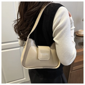 Vue latérale du sac sous le bras en cuir grainé beige porté par un mannequin en intérieur