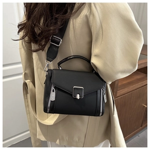 Close-up of a black textured leather crossbody bag with silver hardware and a wide strap