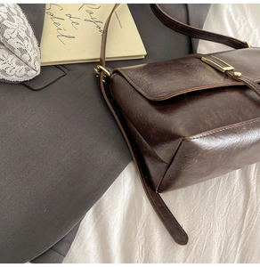 Detail view of vintage dark brown leather bag with golden metallic buckle and fine texture