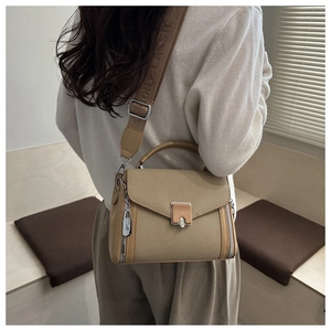 Detail of khaki leather crossbody bag featuring a wide jacquard strap and metal lock