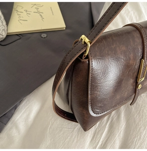 Detail of vintage brown leather handbag featuring gold metal clasp and stitching