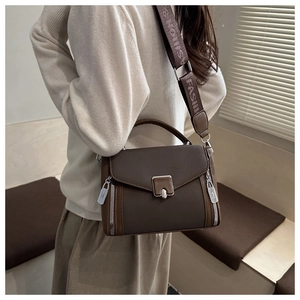 Detail of dark brown pebble leather crossbody bag with wide lettered strap and silver lock