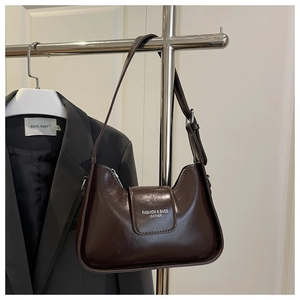 Détail d'un sac sous le bras demi-lune marron foncé en similicuir brillant avec lanière