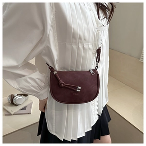 Macro detail of wine red matte leather crossbody bag featuring stylish knot shoulder strap
