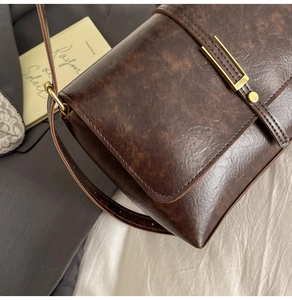 Detailed close-up of vintage brown leather texture and gold metallic lock on a flap bag