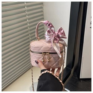 Detail of pink quilted mini bag with silk scarf bow and gold-tone chain strap