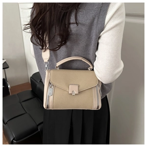 Detailed view of khaki crossbody handbag with metal buckle worn by a model
