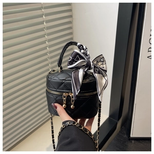 Close-up of black quilted mini vanity bag with chain strap and scarf wrapped handle