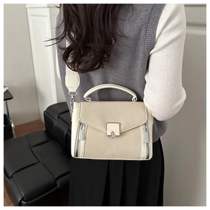 Rear view of model wearing a minimalist beige crossbody bag with metal buckle and wide strap