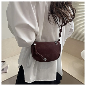 Back view of a burgundy saddle crossbody bag with knot strap detail and matte finish
