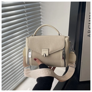 Detail of beige canvas crossbody bag with decorative side zippers and woven logo strap