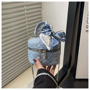 Detail of light blue quilted mini bag with silk scarf on handle and gold chain strap
