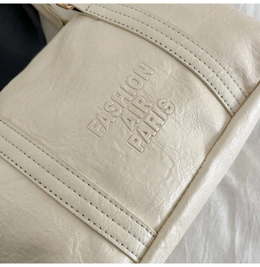 Close-up of cream leather pillow bag with Fashion Air Paris engraving and fine stitching