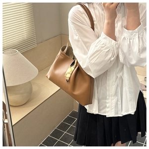 Close-up of brown faux leather tote bag with a colorful decorative silk scarf on the handle