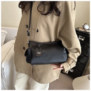 Detail of minimalist black matte crossbody bag with adjustable strap and fashion tag
