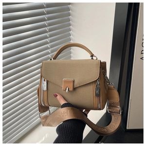 Detail of khaki canvas crossbody bag with flip-top cover and wide woven shoulder strap