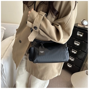 Close-up of black matte leather shoulder bag with side pockets and fashion tag
