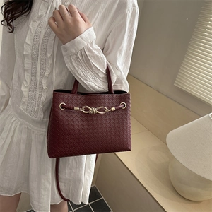Burgundy woven handbag with gold knot clasp shown at a 45-degree angle