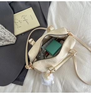 Overhead view of cream crossbody bag showing interior space for makeup and perfume