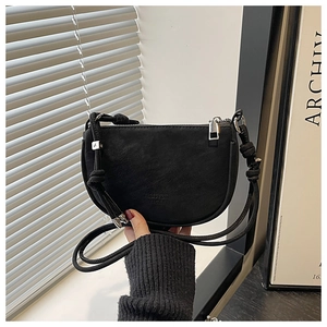 Detail of a black matte saddle crossbody bag with embossed lettering and adjustable strap