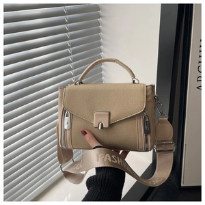 Close-up of beige canvas crossbody bag featuring wide logo fabric strap and metal lock