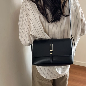 Vintage French black shoulder bag with gold buckle displayed on model in lifestyle setting