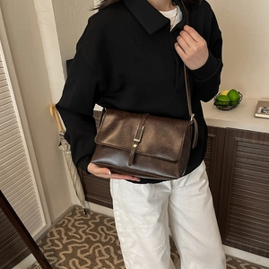 Retro dark brown crossbody bag with metallic lock shown in a stylish lifestyle photo