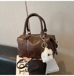 Detail of dark brown vintage texture handbag with sheep charm and embossed logo