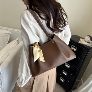 Deep brown matte leather tote bag with white contrast stitching and decorative silk scarf