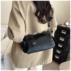 Detail of black PU leather shoulder bag featuring silver hardware and side pocket detail