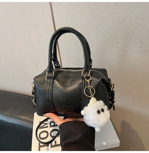Detail of vintage black Boston bag with gold hardware and a fluffy monster charm