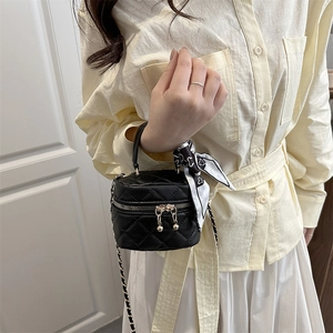 Mini black quilted handbag with chain strap and scarf handle shown by model