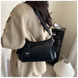Detail of minimalist black PU shoulder bag with adjustable silver buckle and side pocket
