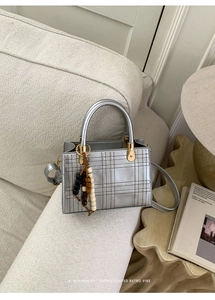 Detail of silver crossbody bag with quilted stitching and decorative wooden beads