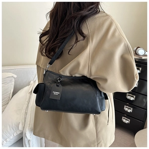 Close-up of black leather shoulder bag with fashion tag and metal bottom feet