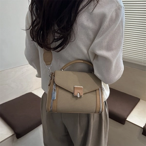 Minimalist khaki canvas crossbody bag with silver buckle worn by a model in a studio