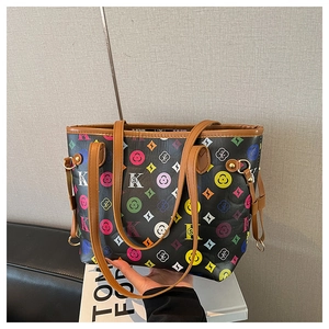 Close-up of retro monogram tote bag with colorful pattern and brown leather trim handles