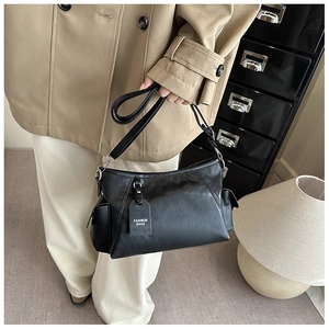 Detail view of the black leather underarm bag featuring a Fashion Bags charm and side pocket