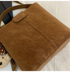 Nahaufnahme der braunen Wildleder-Beuteltasche mit feiner Textur und Bärenanhänger
