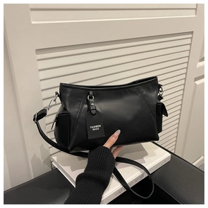Detail of minimalist black faux leather bag featuring silver hooks and a fashion tag