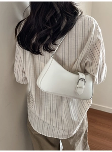 Detailansicht einer weißen Hobo-Tasche mit dekorativem Schnallenriemen und glattem Matt-Finish