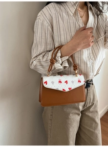 Detail of printed shoulder bag featuring cute bear pattern and tan leather texture