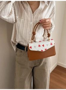 Detail of trendy small square bag featuring heart and bear prints with golden hardware
