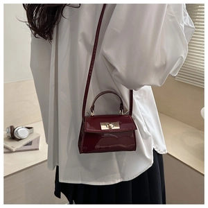 Détail du mini sac bordeaux en cuir verni avec fermoir tournant doré et poignée
