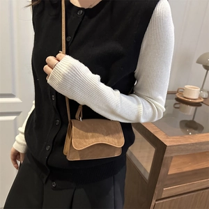 Petit sac carré minimaliste vintage marron en daim porté par un mannequin en intérieur