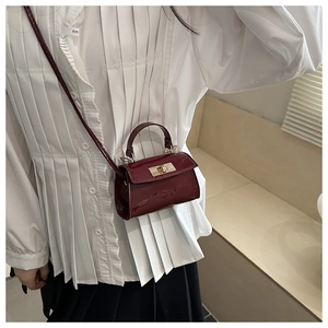 Détail du mini sac bandoulière en cuir verni bordeaux avec fermoir rotatif doré