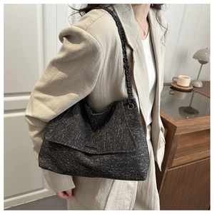 Detail einer dunkelgrauen Tweed-Umhängetasche mit schwarzer geflochtener Kette