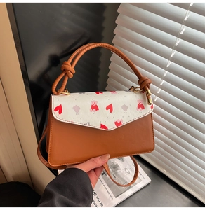 Detail of a brown and white tote bag with a cartoon bear print and knotted top handle