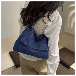 Detailansicht der blauen Denim-Tragetasche mit silbernem Metallstab und Kettengurt